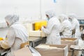 Four anonymous workers on uniforms packaging containers at industrial factory
