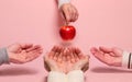Four arms are outstretched in the direction of a single Apple. The concept of competition and rivalry in the implementation of a Royalty Free Stock Photo