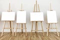 Four art studio easels with blank white painting frames Royalty Free Stock Photo