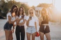 Four attractive women are standing on car parking with smartphones