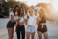 Four attractive women are standing on car parking with smartphones