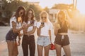 Four attractive women are standing on car parking with smartphones