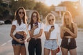 Four attractive women are standing on car parking with smartphones