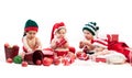 Four babies in xmas costumes playing among gifts Royalty Free Stock Photo