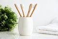 Four bamboo toothbrushes in a mug with a towel