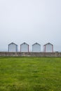 Beach huts perched on a lush, grassy meadow, with a breathtaking horizon of the sea beyond