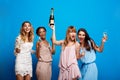 Four beautiful girls resting at party over blue background.