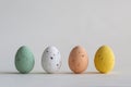 Four pastel colored chocolate Easter eggs in a row, on white background with copy space