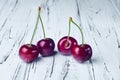 Four beautiful red cherries on a white wooden table