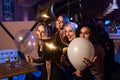 Four beautiful young Caucasian women holding balloons having night out together in trendy bar