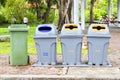 Four bins are on the sidewalk in the park. Royalty Free Stock Photo