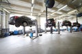 Four black cars on lifts in small service station