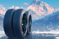 Four black tires against a winter mountain backdrop scene
