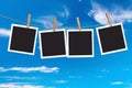 Four blank instant photo frames hanging on a rope on blue sky background Royalty Free Stock Photo