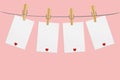 Four blank paper with red heart hanging on the wooden cloth pegs