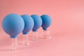 Four blue cosmetic vacuum jars of different sizes made of glass and rubber on pink background