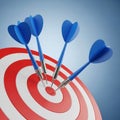 Four blue darts embedded in a red and white bullseye target dartboard game Royalty Free Stock Photo
