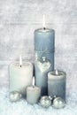 Four blue, grey and white burning christmas candles with snow in Royalty Free Stock Photo
