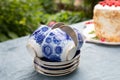 Four blue tea cups are stacked on a stack of saucers on the table in the garden, cake in the background. Everyday Royalty Free Stock Photo