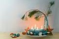 Four blue turquoise candles for Advent, Christmas decoration, wooden stars on a plate and a vase with pine branches, copy space,