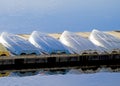 Four boats lined up on in storage a pier in a blue lake.