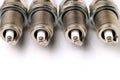 Four brand new unused spark plugs on white background