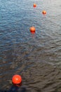 Four bright orange buoys floating on river water surface