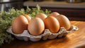 Four brown eggs nestled in a cardboard carton on a wooden surface with herbs