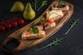 Four bruschettas lay on wooden board. Appetizers with tomato, mozzarella, pesto, salmon and roast beef Royalty Free Stock Photo