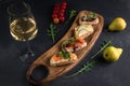 Four bruschettas lay on wooden board. Appetizers with tomato, mozzarella, pesto, salmon and roast beef. A glass of white wine on Royalty Free Stock Photo
