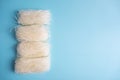 Four bundles of dry funchosa noodles on a blue background with space for text