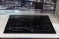 Four-burner black hob integrated into a white table with a black glass wall with a pattern in the kitchen Royalty Free Stock Photo