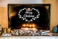 Four burning advent candles, beautiful decorated setup light TV in Background textspace saying merry christmas Royalty Free Stock Photo