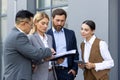 Four business people discussing financial results of achievement, mature men and women outside office building Royalty Free Stock Photo