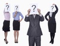 Four business people holding up paper with question mark, obscured face, studio shot Royalty Free Stock Photo