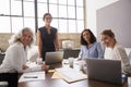 Four businesswomen in a meeting room looking to camera