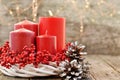 Four candles in a white wreath with red berries on a wooden rustic background with lights. advent calendar for Christmas Royalty Free Stock Photo