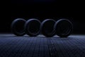 Four car tires, lit by cold light from above in a tunnel on a dark background. Royalty Free Stock Photo