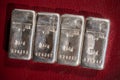 Four cast silver bars weighing 250 grams each on a burgundy textured background.