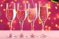 Four champagne glasses against pink background with blurred garland Royalty Free Stock Photo