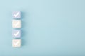 Four checkmarks on light toy blocks against pastel blue background with copy space