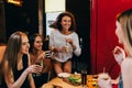 Four cheerful girlfriends having fun chatting and laughing eating and drinking in fast food restaurant