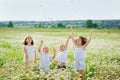 Four children in a blooming chamomile meadow. Friends are having fun in a field of daisies. Boys and girls throw up flowers and Royalty Free Stock Photo