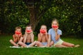 Four children are eating a red watermelon in the garden against a background of greenery. Kids eat fruit outdoors. A healthy snack Royalty Free Stock Photo