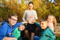 Four children are looking into the camera, small children are sitting next to a pregnant woman and holding their hands on their