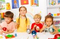 Four children paint New Year balls for Xmas tree