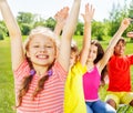 Four children sitting in row with hands up