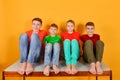 Four children squatting barefoot, a bright colorful juicy photo of teenagers sitting in colored clothes