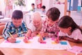 Four children writing together on a broadsheet. Royalty Free Stock Photo