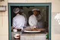 Four chinese chefs making traditional food in a kitchen - seen through an open window frame in a building at street level